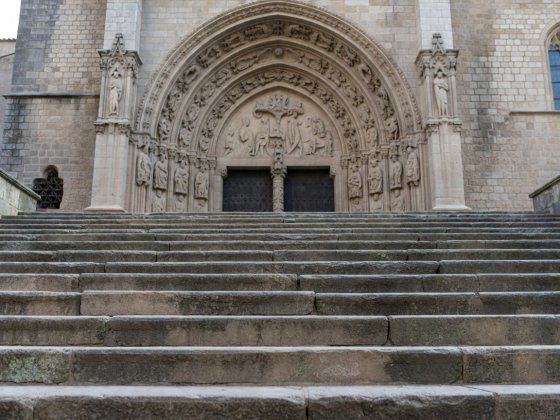 Looking up the wide stone stairs leading to an ancient carved stone cathedral portal under soft daylight