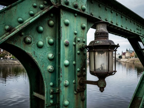 Close-up of green wrought-iron rivets and old gas lantern on a historic footbridge over the river in Wroclaw